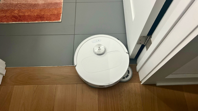 Roborock Qrevo Master robot vacuum cleaning tile and hardwood floor with rug and door in peripherals