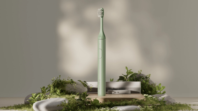 Green Suri electric toothbrush and charger displayed on rocks and moss