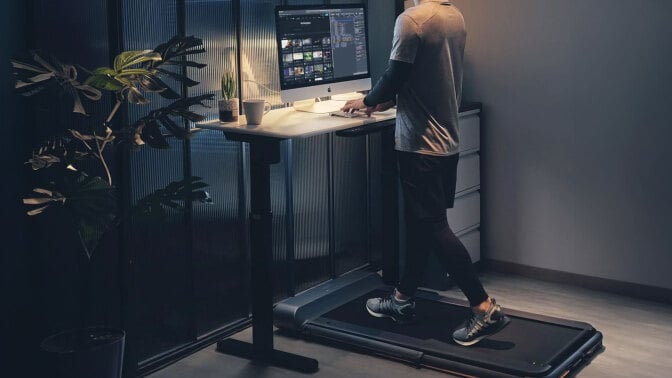 man using iQ Slim Walking Pad at night while working