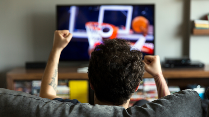 man watching basketball game from the couch