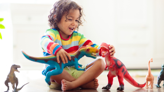 small child laughing and playing with dinosaur toys 