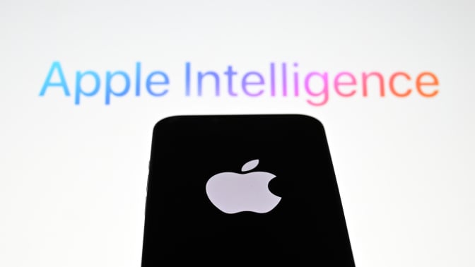 the 'Apple' logo is displayed on a mobile phone screen in front of a computer screen displaying Apple Intelligence logo