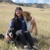 Person sitting in a field of grass with two dogs