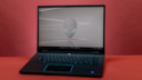 the Alienware M16 R2 against a reddish-orange background